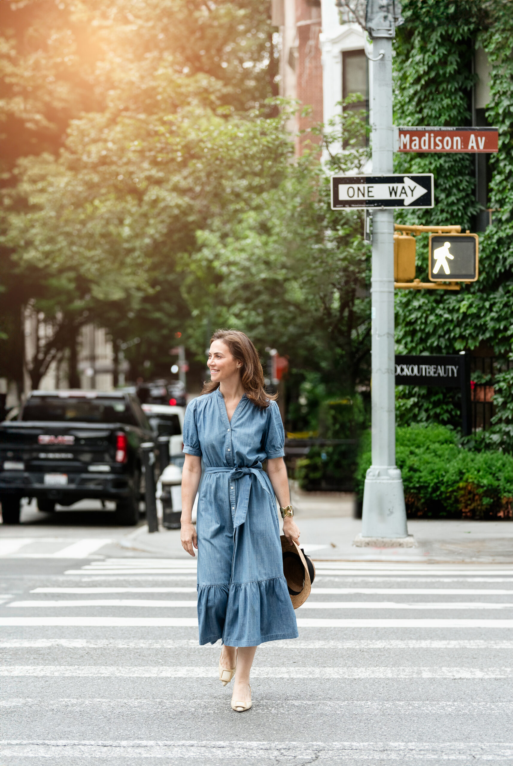 Woman in denim dress crossing street, lifestyle portrait.