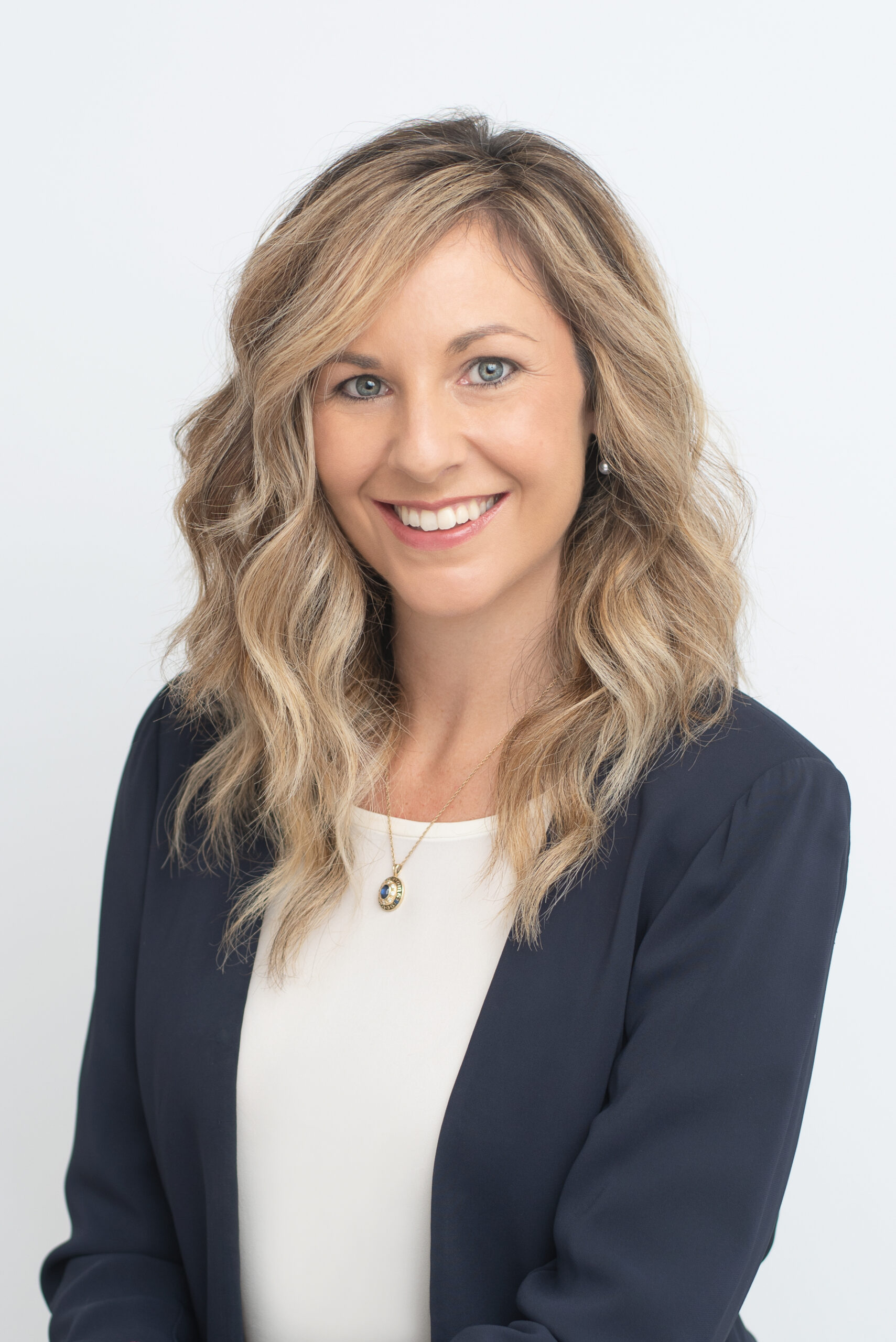 Woman in navy blazer and white top, business portrait.