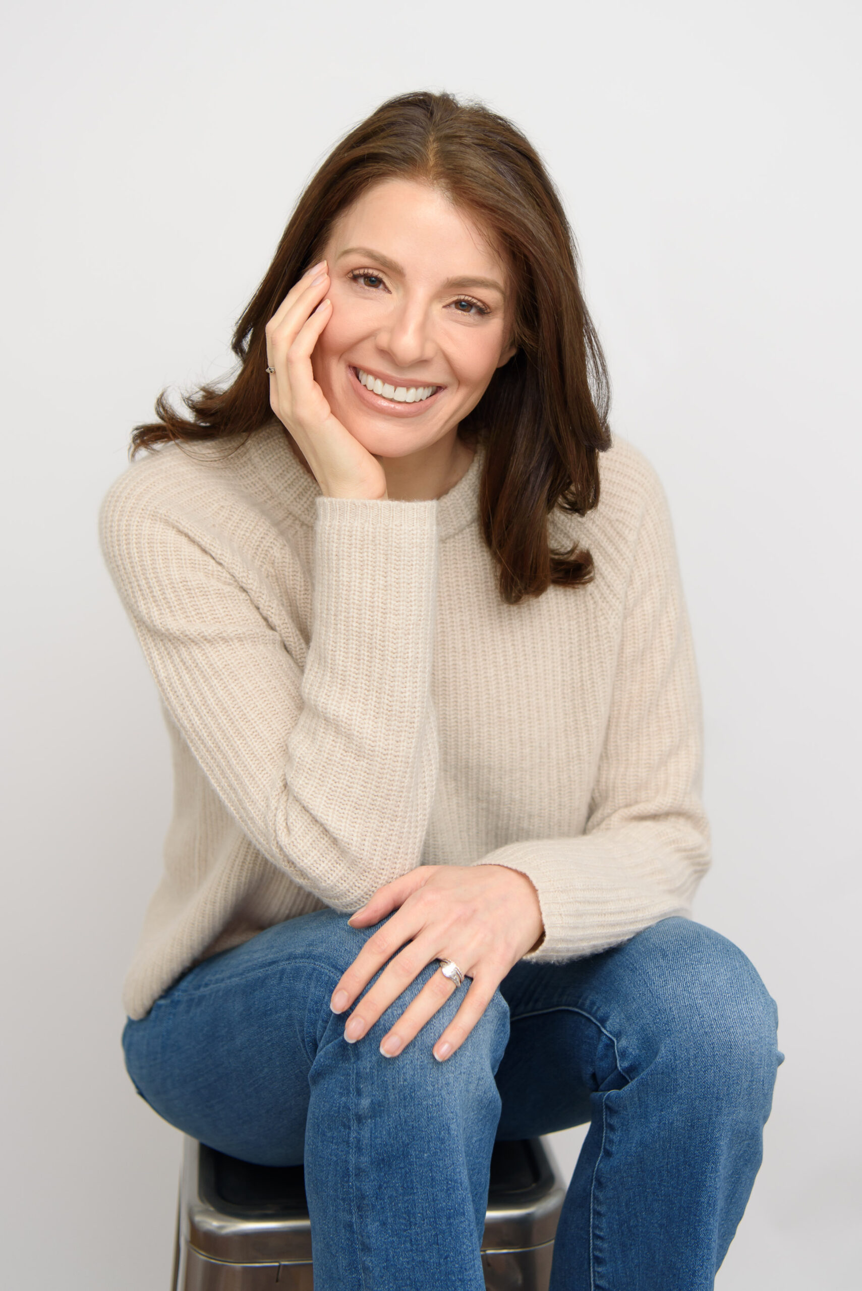 Woman in beige sweater and jeans, smiling headshot.