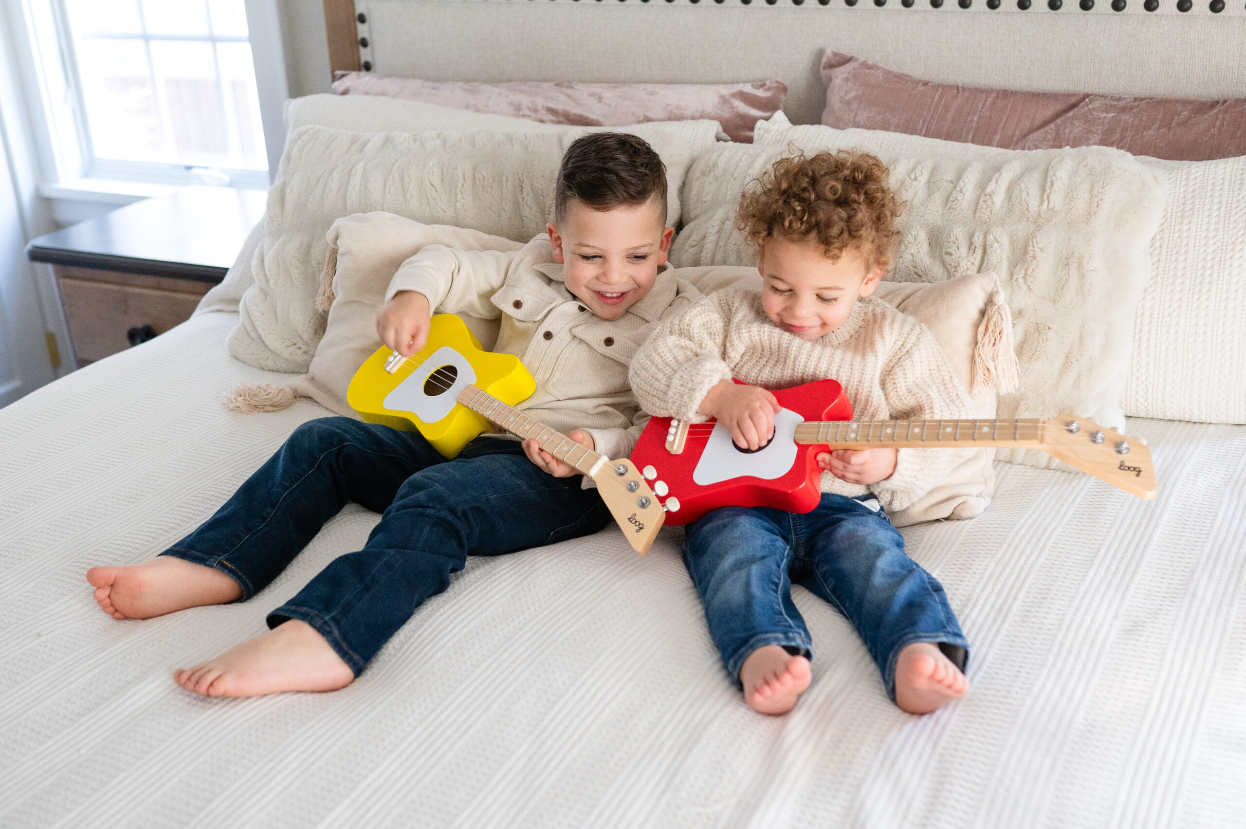 older sibling brothers taking a break during their baby sister's newborn session playing with their toy guitars
