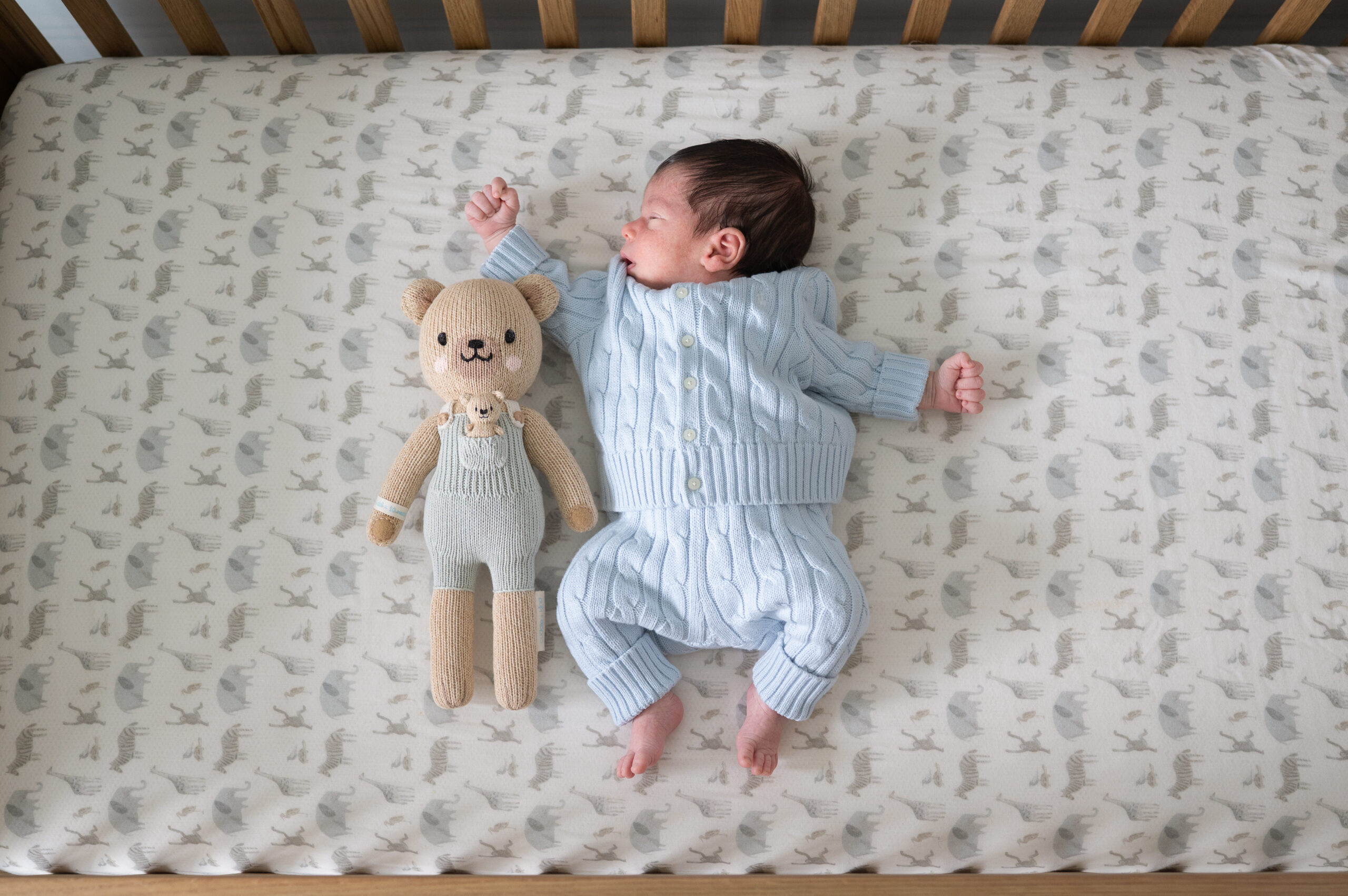sleeping newborn baby in crib with knitted toy bunny